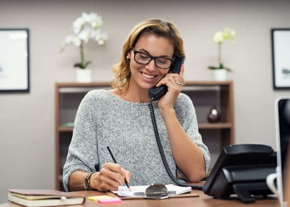 Eine Frau am Telefon bespricht Änderungen bei der Lohnabrechnung für Unternehmen